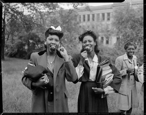 Young women eating caramel apples, including Helen Ruth Daniels in center, and possibly Cora on right, on lawn with building in background, possibly Schenley High School